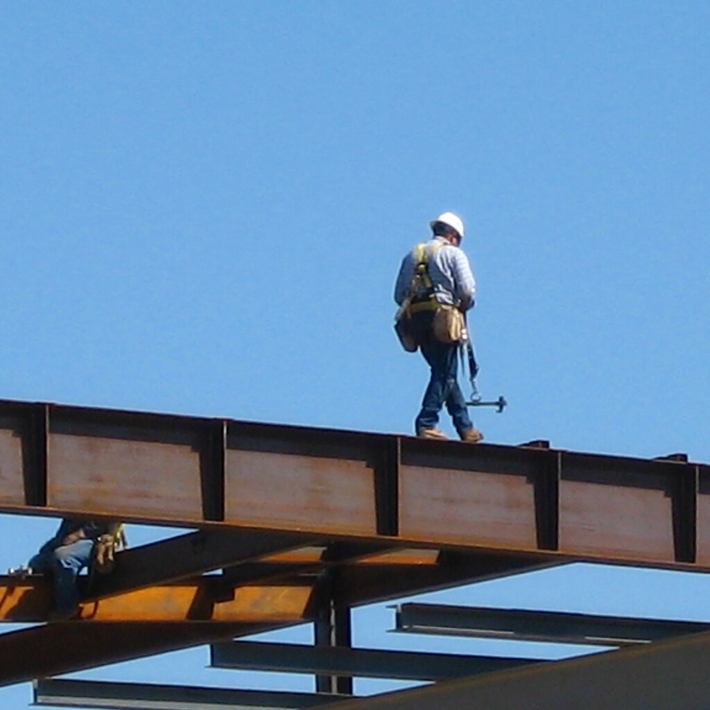 Photo of a man walking along a steel beam