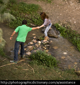 A man helping a woman across a stream