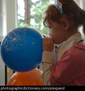 Photo of a little girl blowing up a balloon