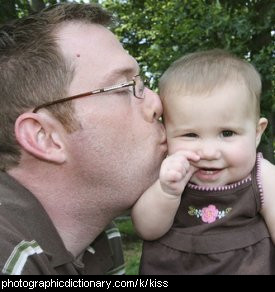 Photo of a man kissing a baby.