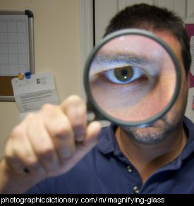 Photo of a man looking through a magnifying glass