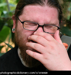 Photo of a man sneezing.
