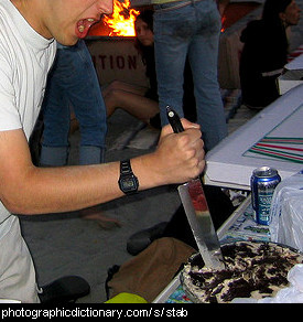 Photo of a man stabbing a cake