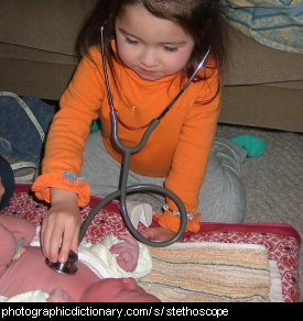 Photo of a little girl using a stethoscope on a baby