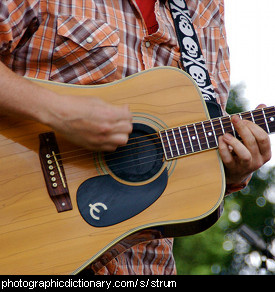 Photo of a man strumming a guitar.