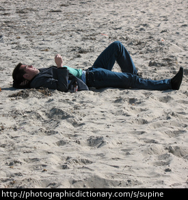 A man lying supine on a beach
