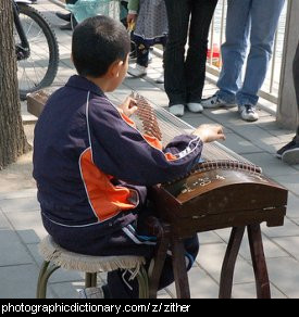 Photo of a boy playing a zither.