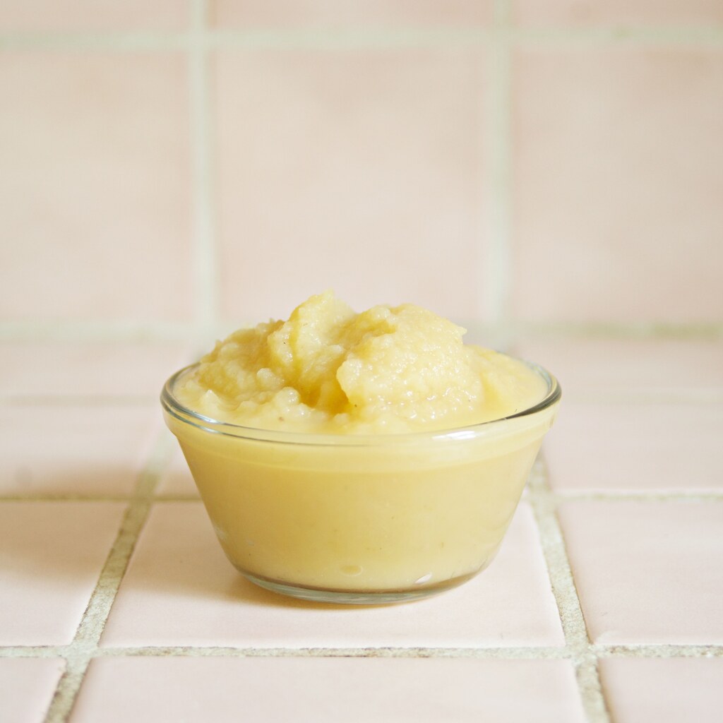 A photo of applesauce in a clear glass bowl on a tiled surface
