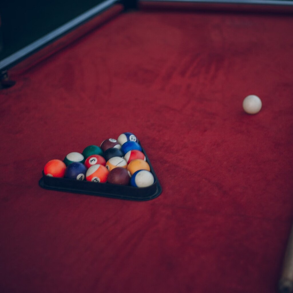 A photo of billiard balls and cues arranged on a table.