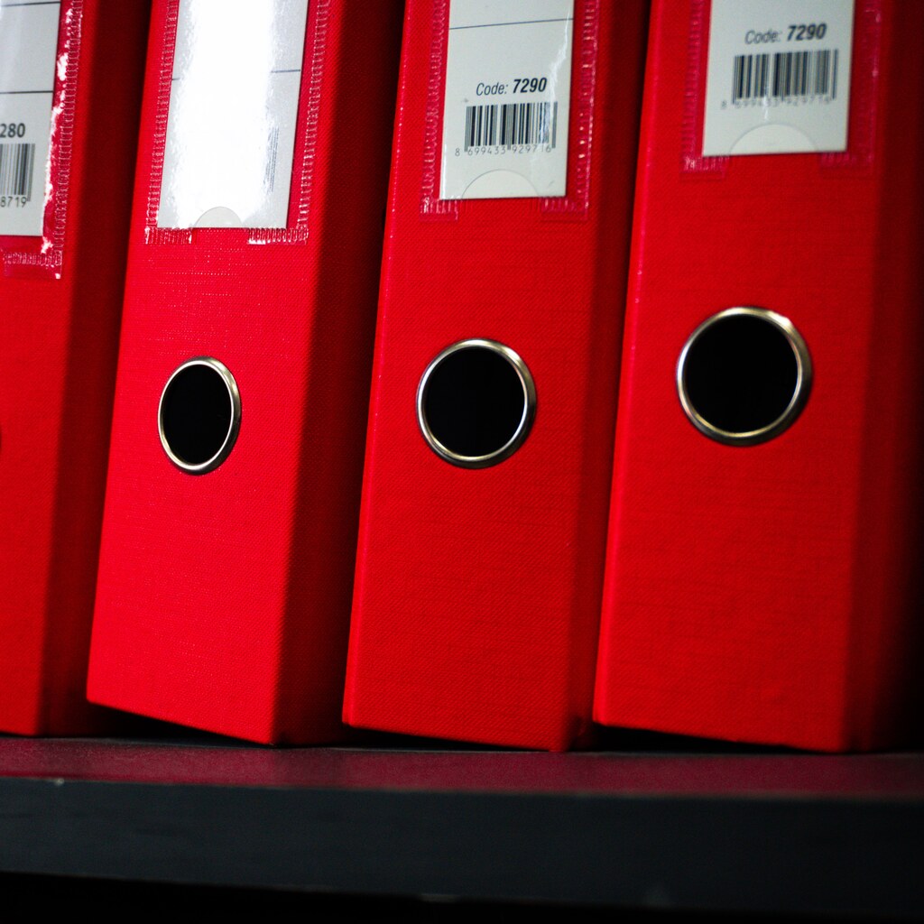 A photo of red ring binders neatly lined up on a shelf