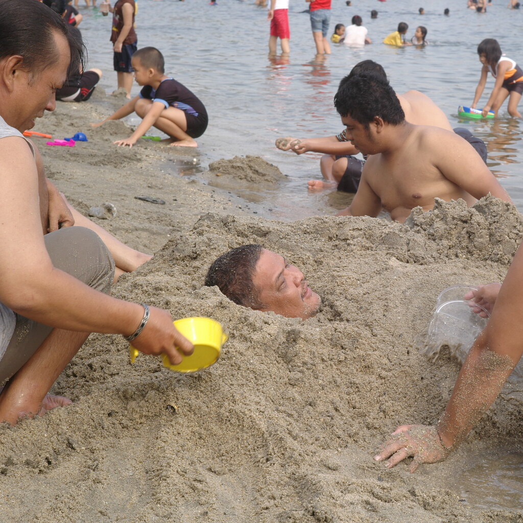 Photo of a man buried up to his neck in sand