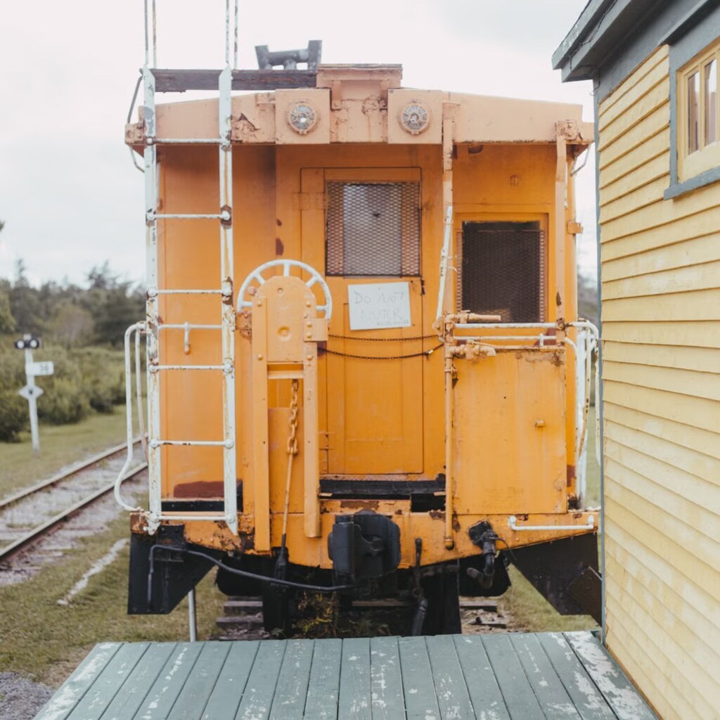 A photo of a yellow caboose on railway tracks.