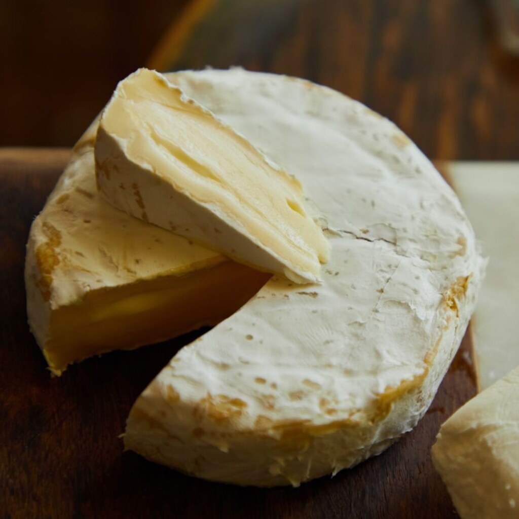 A wheel of Camembert cheese with a wedge cut from it