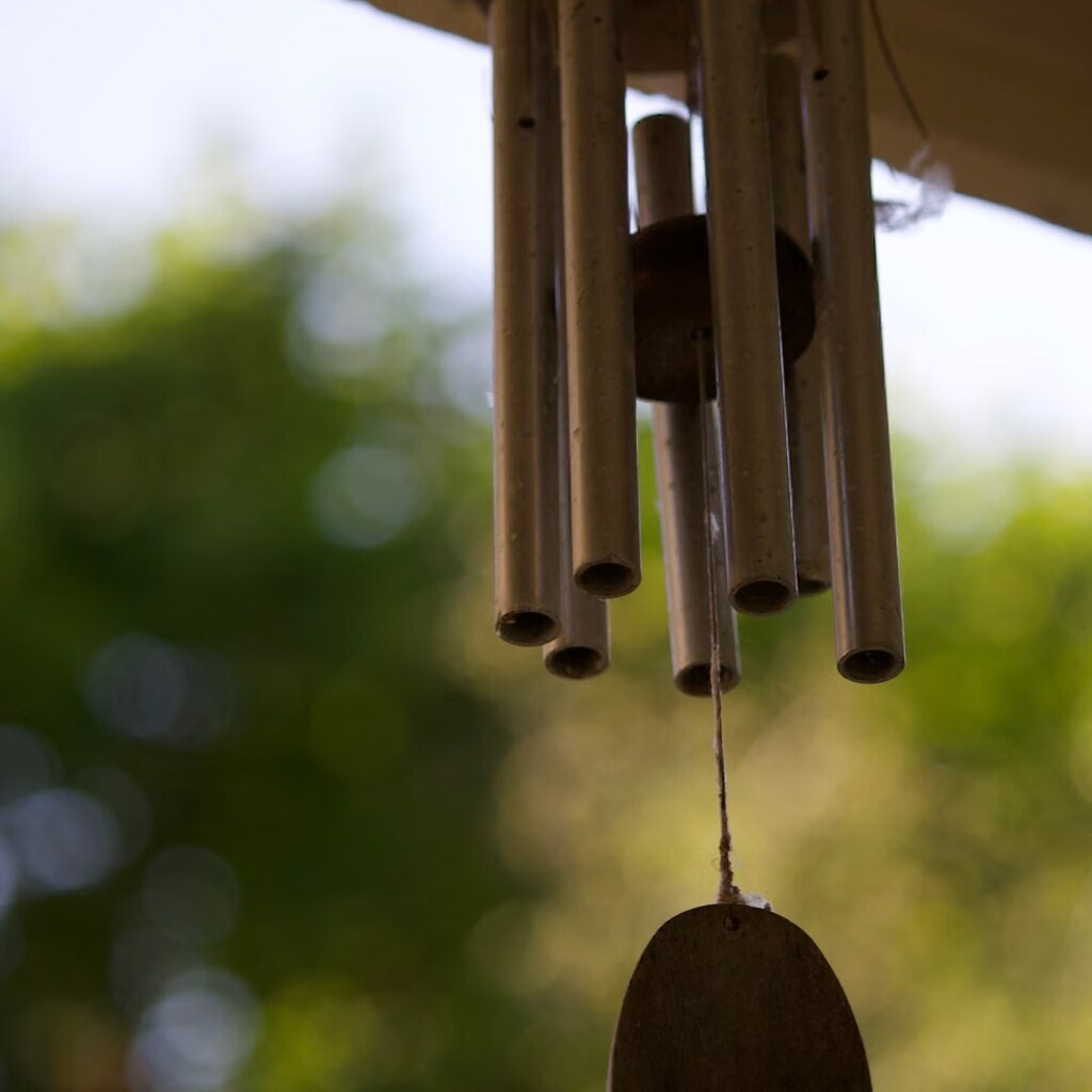 A photo of a metal wind chime hanging outdoors.