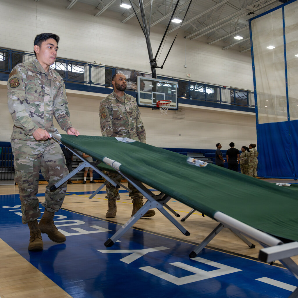 Photo of some people setting up a cot
