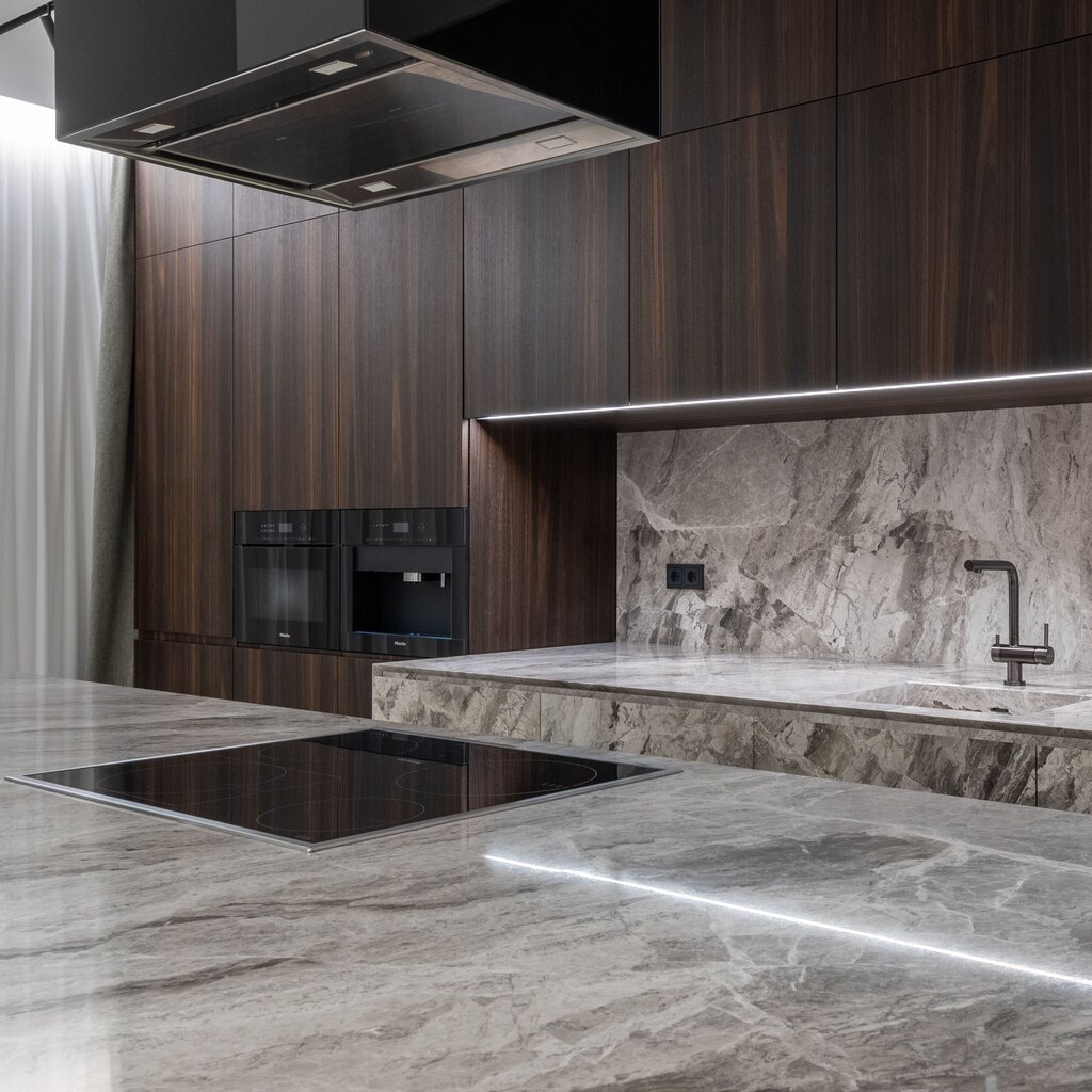 A photo of a marble kitchen countertop with an induction cooktop, sink, and faucet.