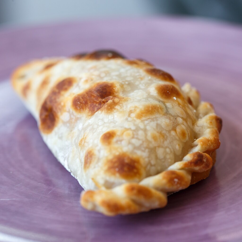 A photo of a baked empanada on a plate.