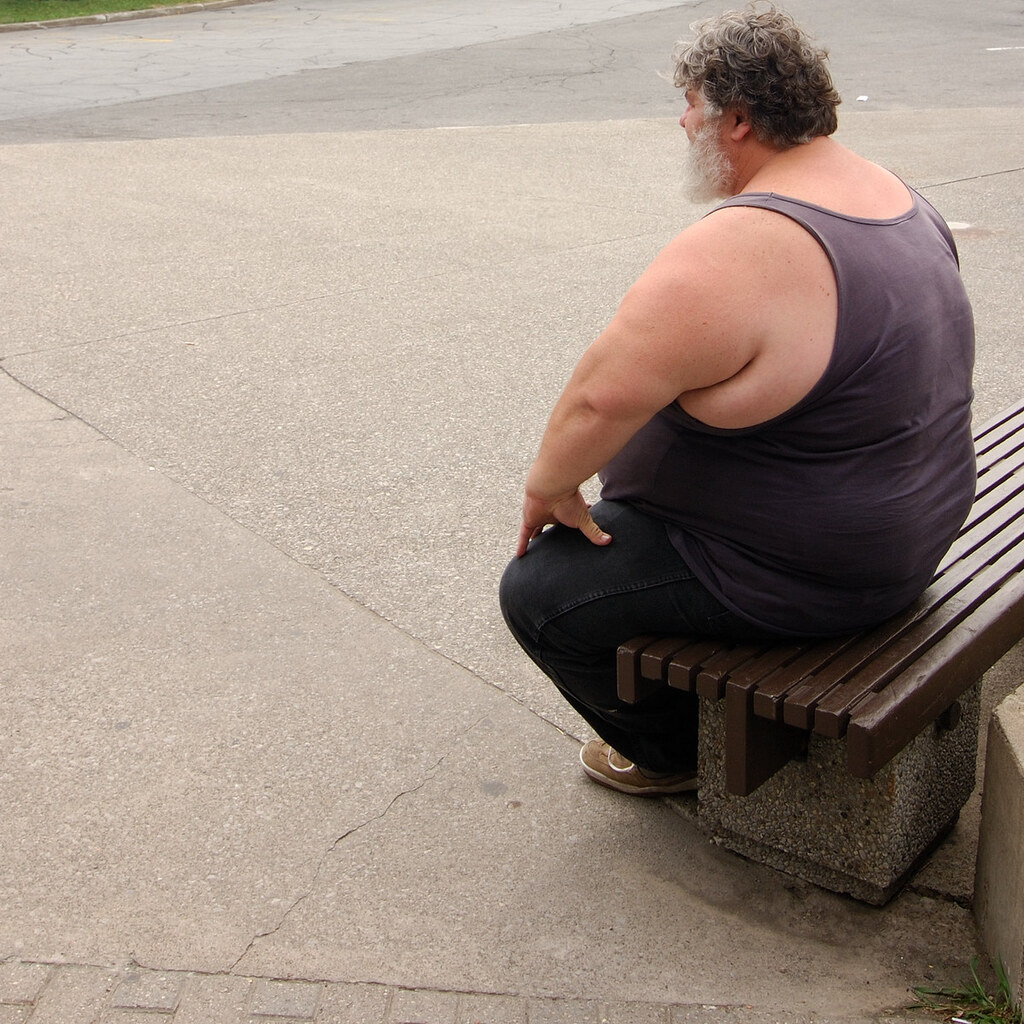 Photo of a fat man sitting on a bench