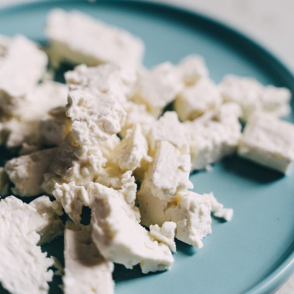 A photo of crumbled feta cheese on a blue plate.