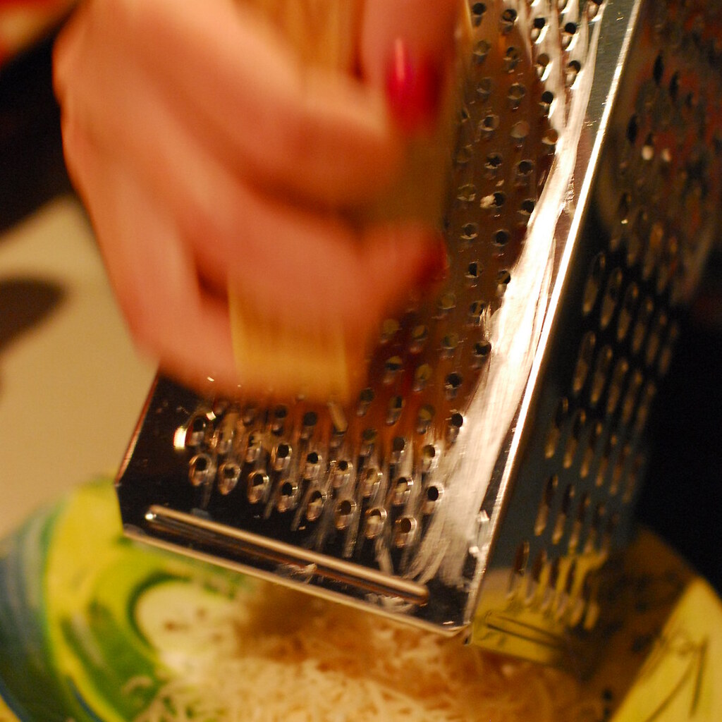 Photo of someone grating cheese.
