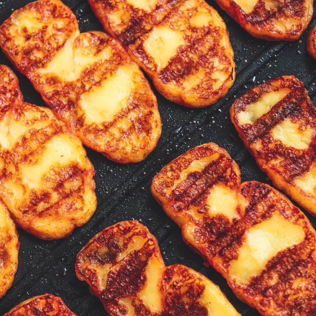 A photo of slices of grilled halloumi cheese in a pan.