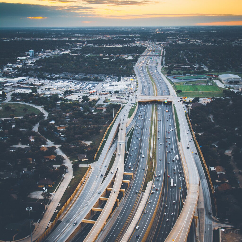 A photo of a busy multi-lane highway stretching through a city at sunset