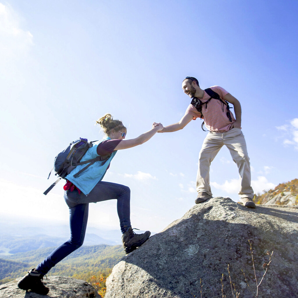 Photo of someone helping someone else while hiking