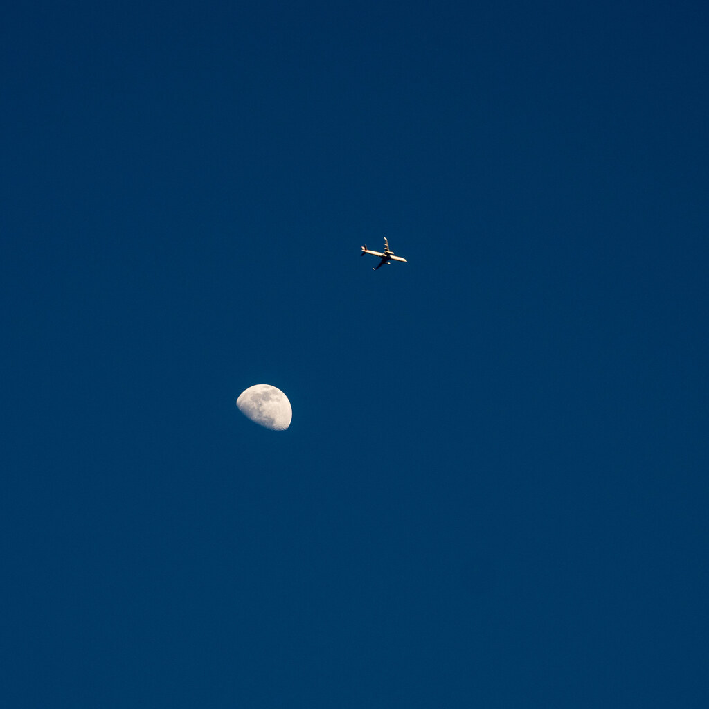 Photo of a plane flying over the moon