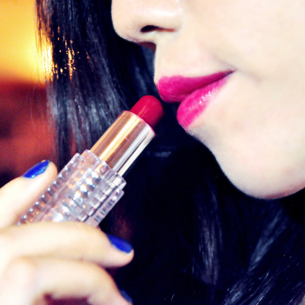 Photo of a woman applying lipstick