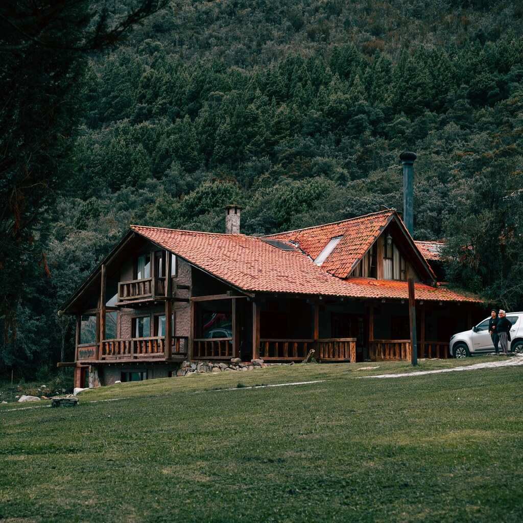 A photo of a wooden lodge surrounded by dense green forest