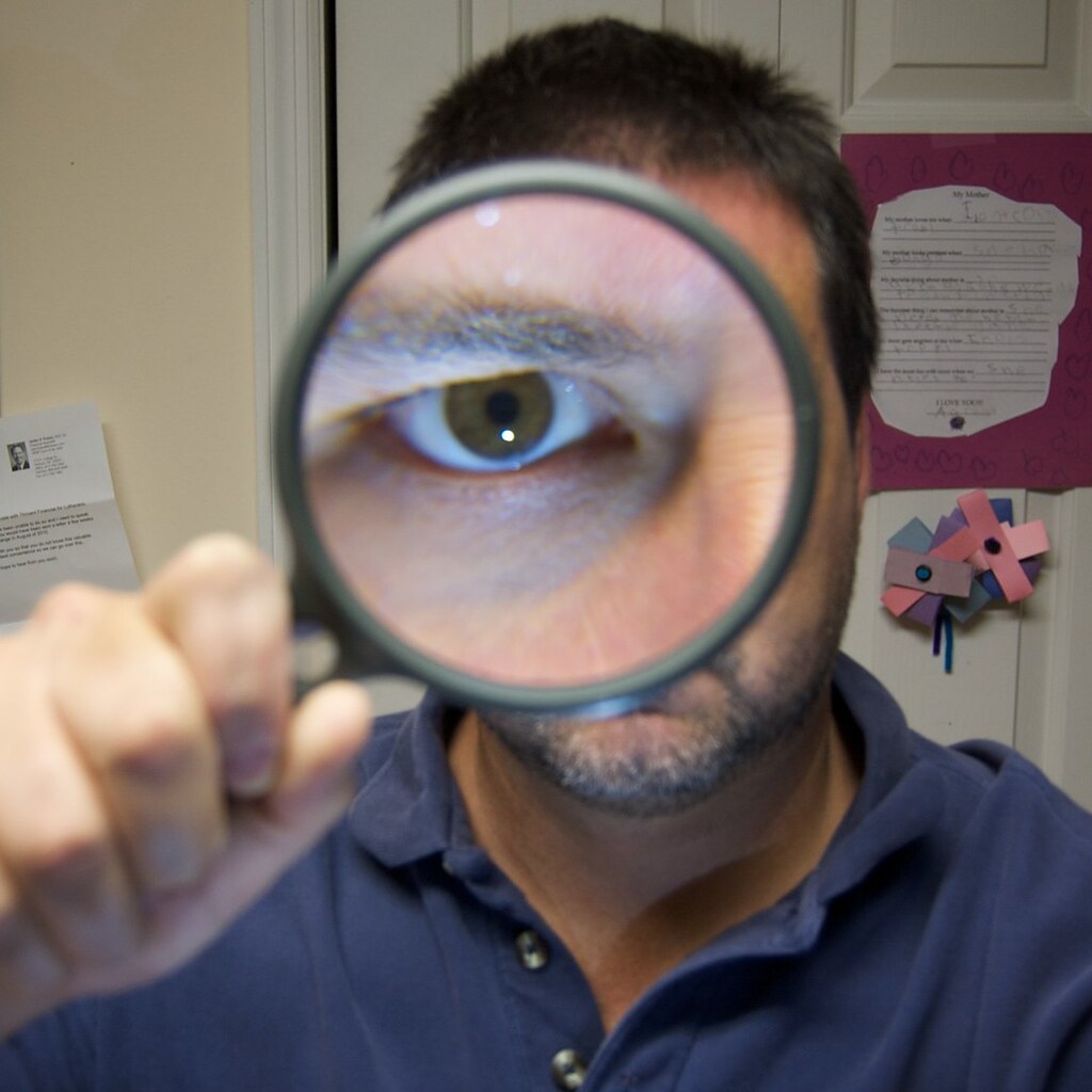 Photo of a man looking through a magnifying glass