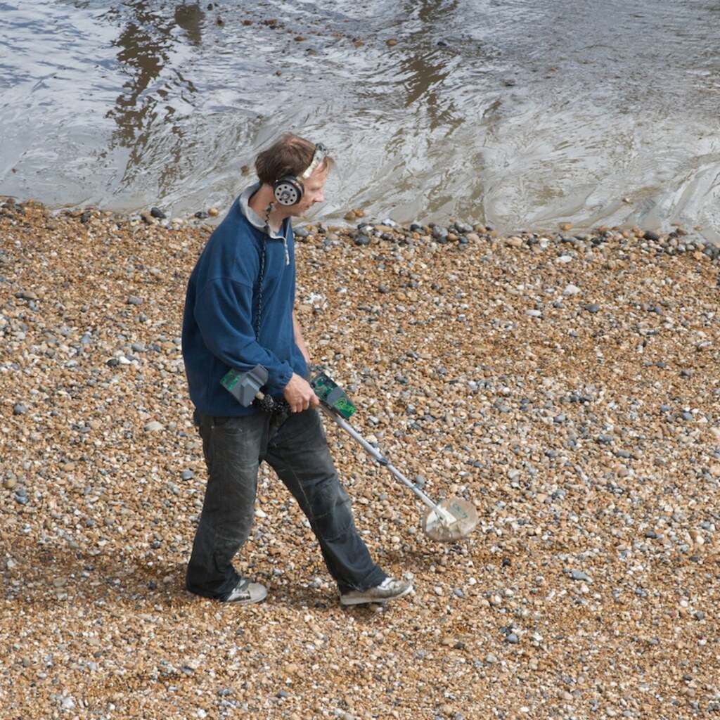 Photo of someone using a metal detector on a beach