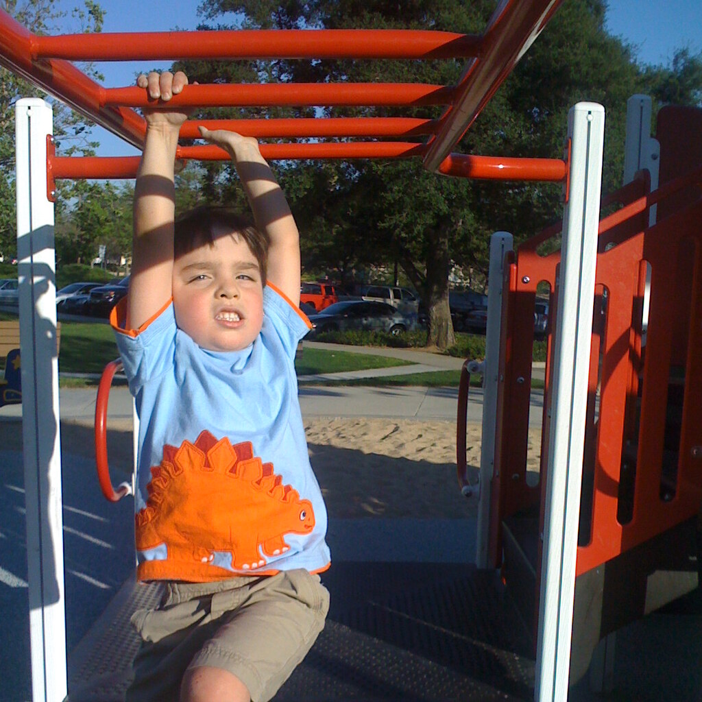 Photo of a boy swinging on the monkey bars