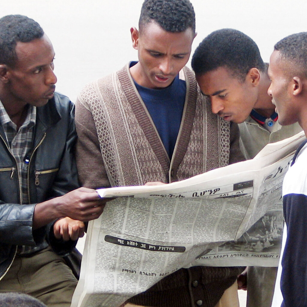 Photo of some men reading a newspaper