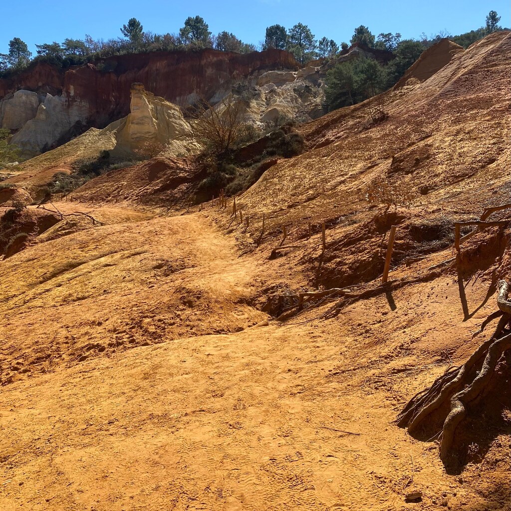 A photo of ochre-colored sandy hills and eroded cliffs beneath a blue sky