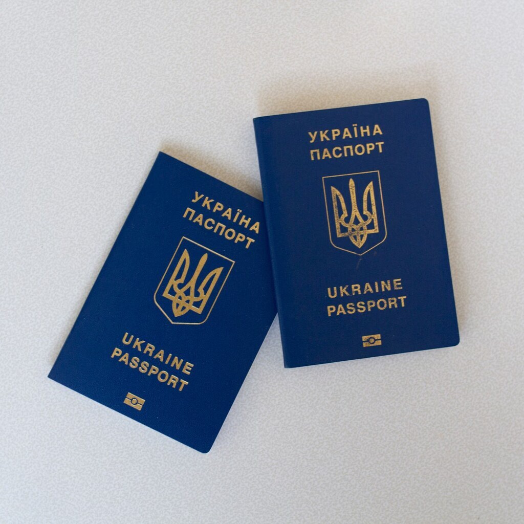 A photo of two passports on a white surface.