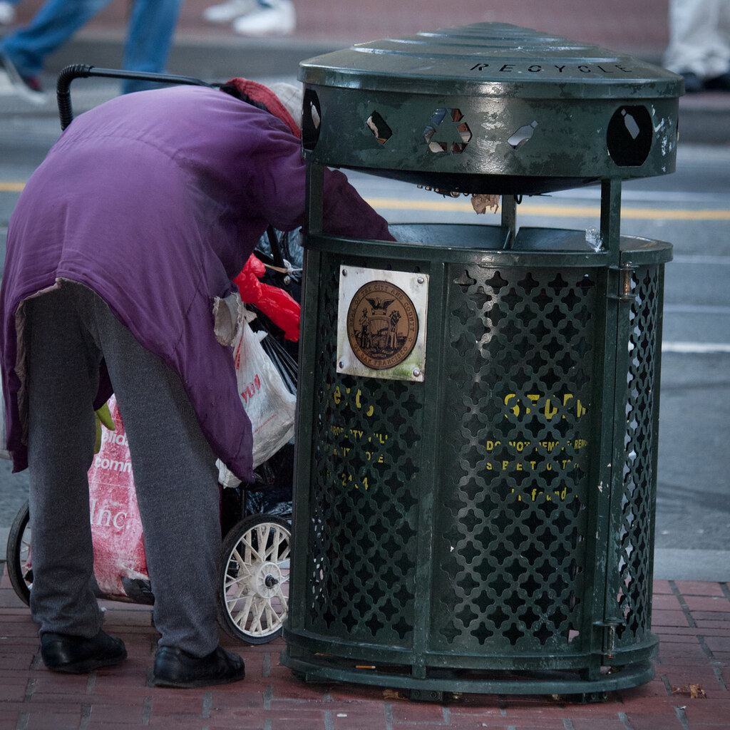 Photo of a woman looking through a trash can