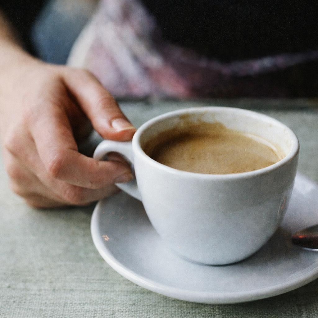 Photo of someone putting down a cup of coffee
