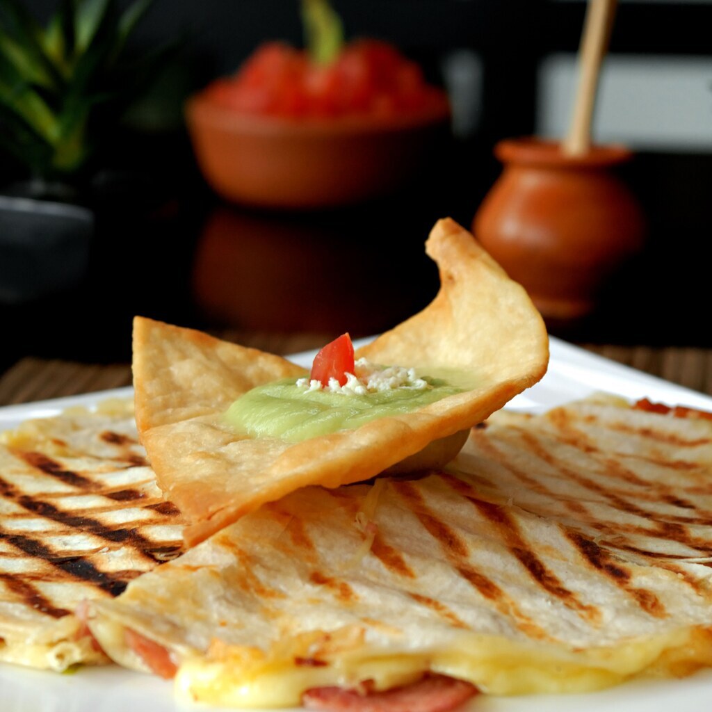 A photo of grilled quesadillas served with salsa and guacamole.