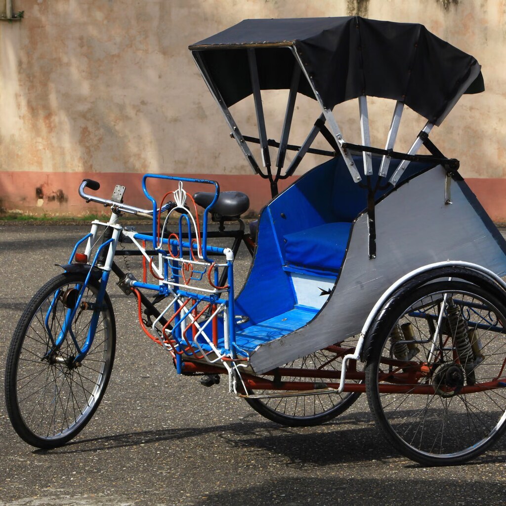 A photo of a blue and red cycle rickshaw parked on a street.
