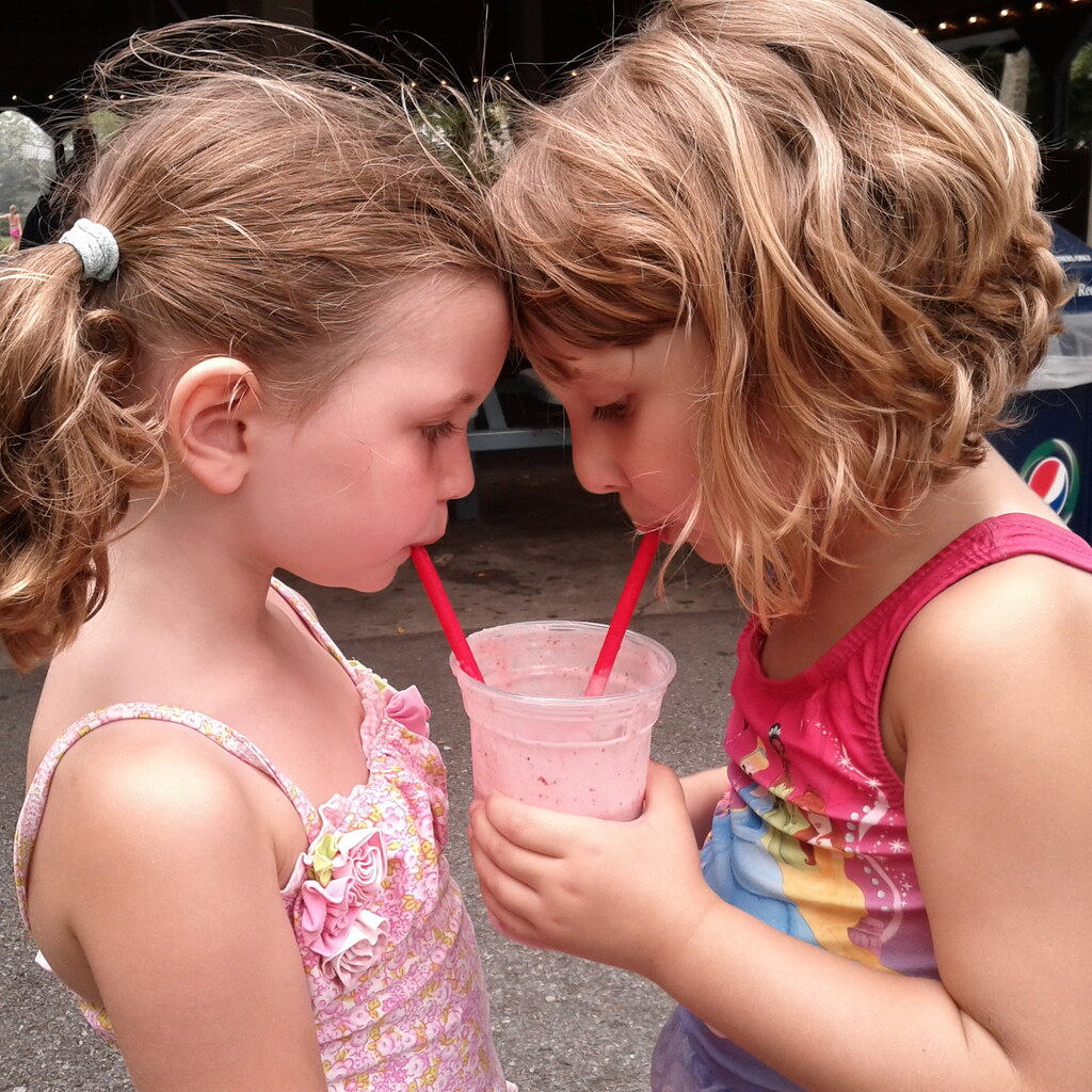 Two children sharing a smoothie