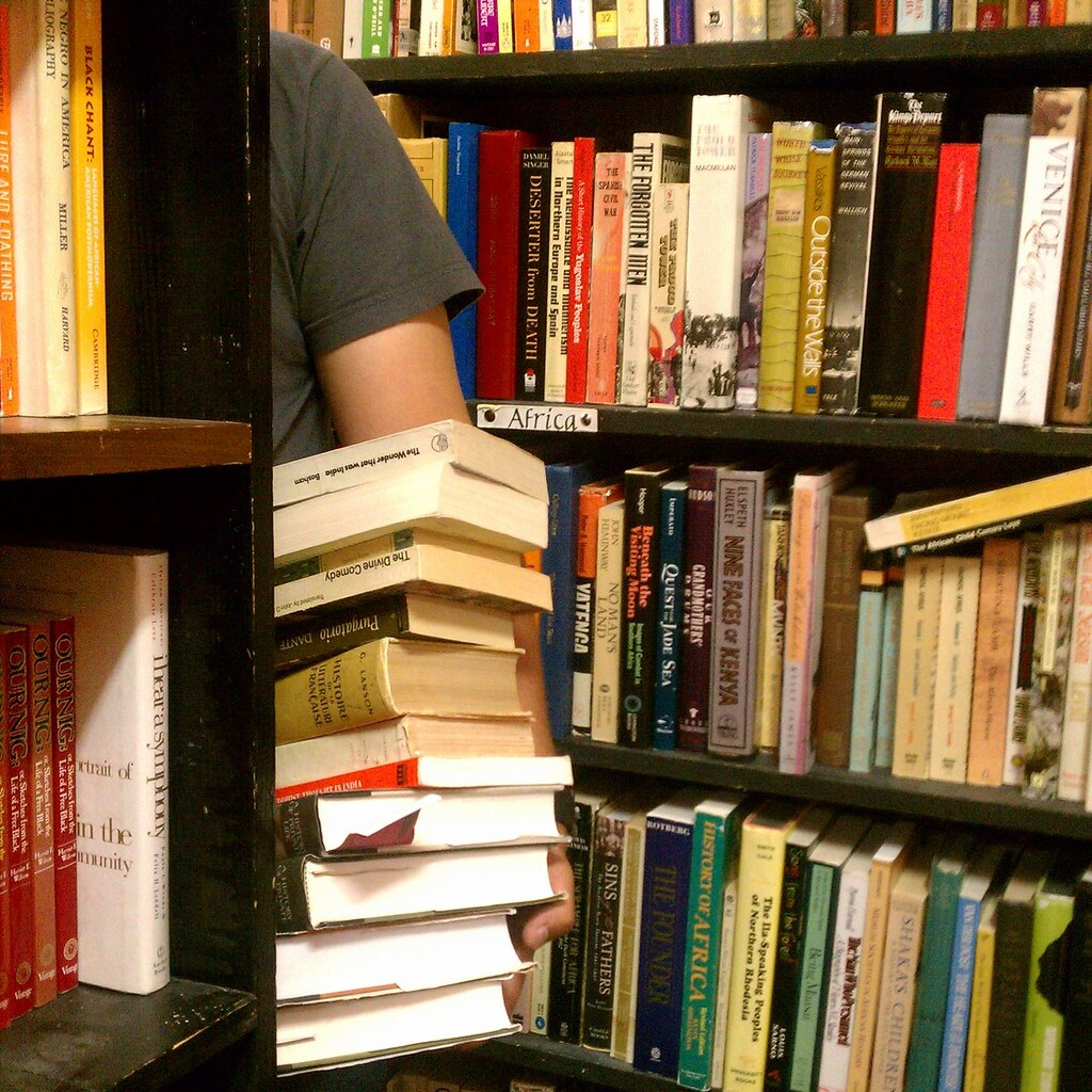 Photo of a man carrying a stack of books
