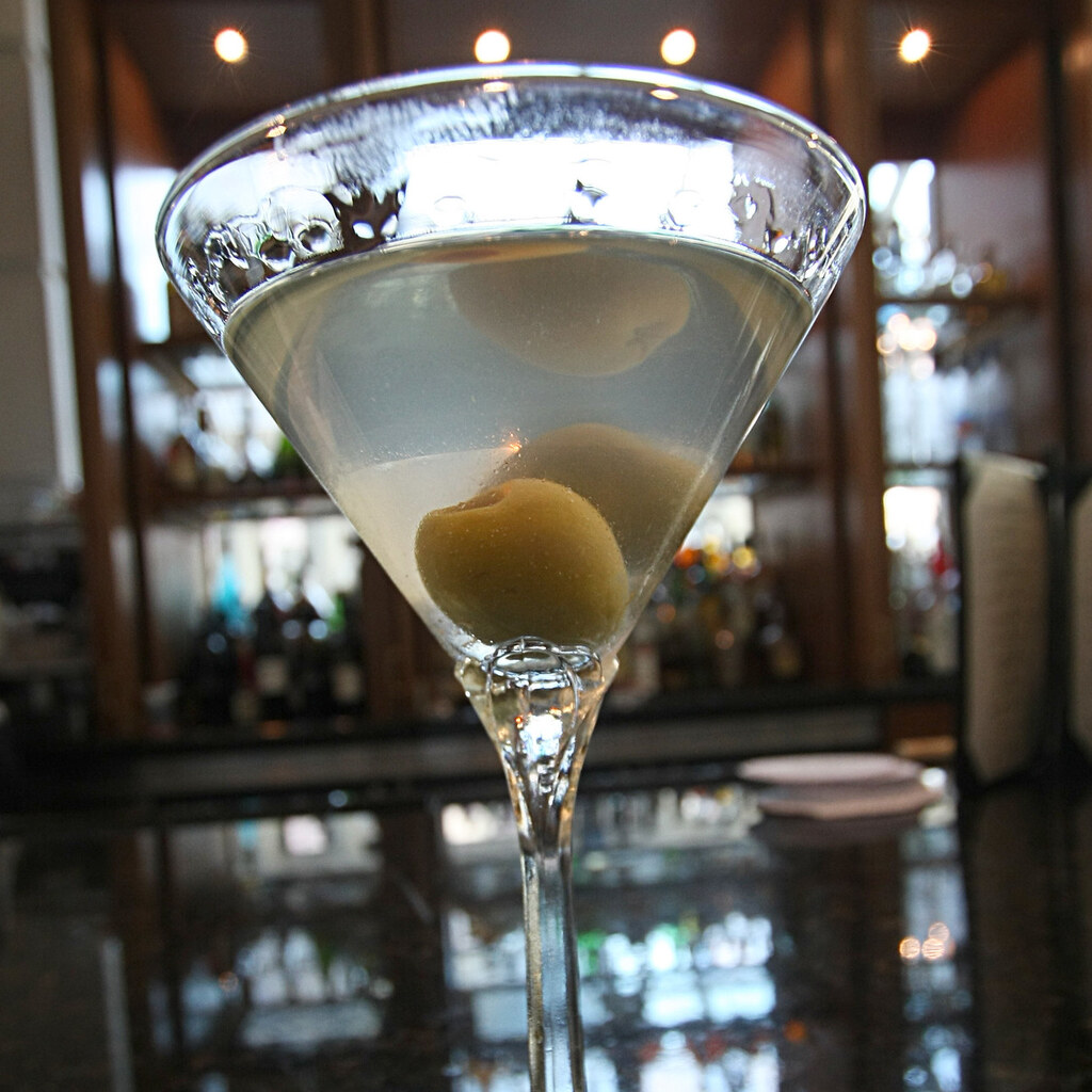 Photo of an olive in the bottom of a martini glass