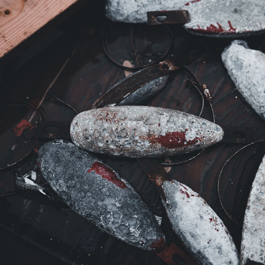 A photo of several weathered fishing sinkers on a dark wooden surface