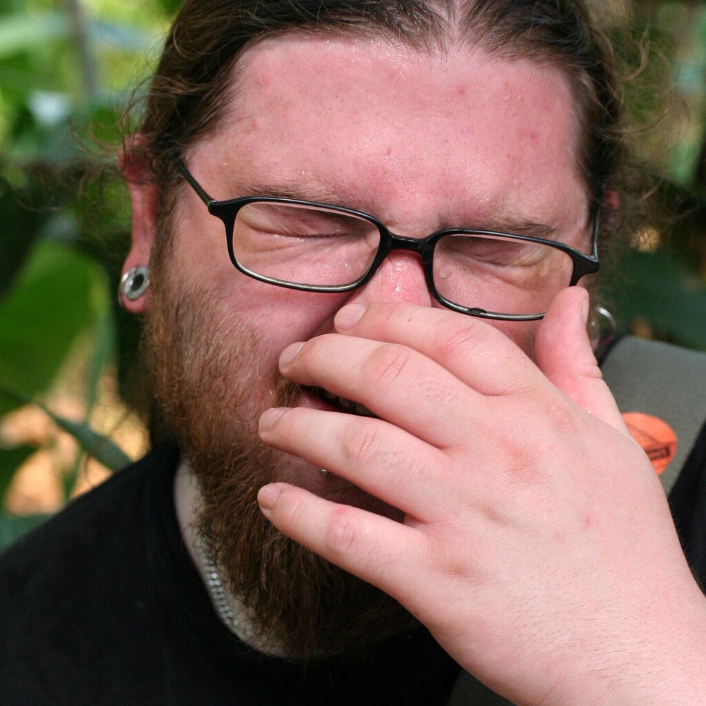 Photo of a man sneezing.