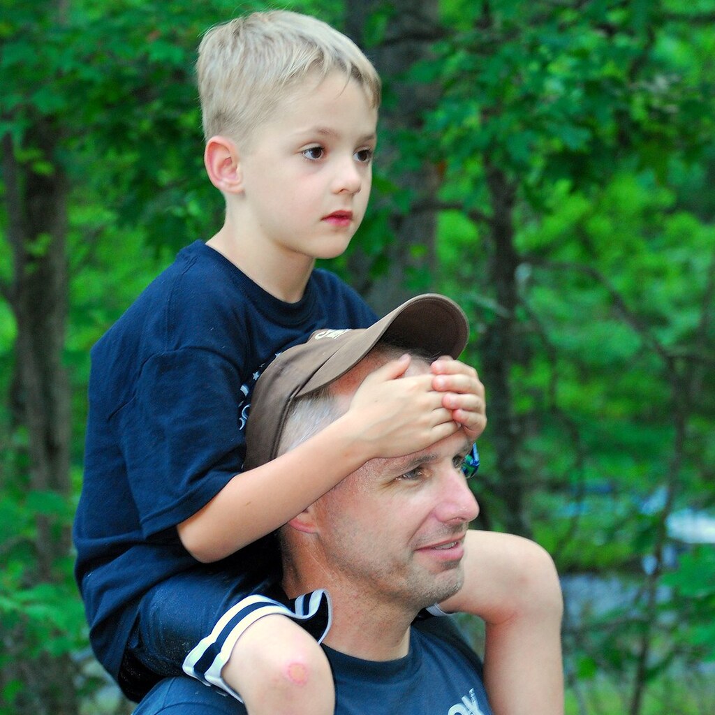 Photo of a boy having a piggyback ride on his father's shoulders