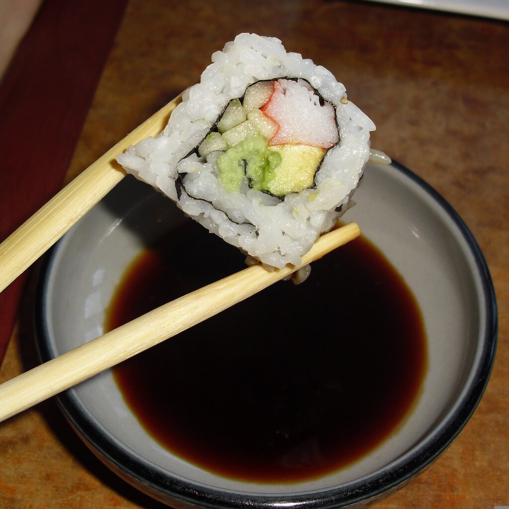 Photo of sushi about to be dipped in soy sauce