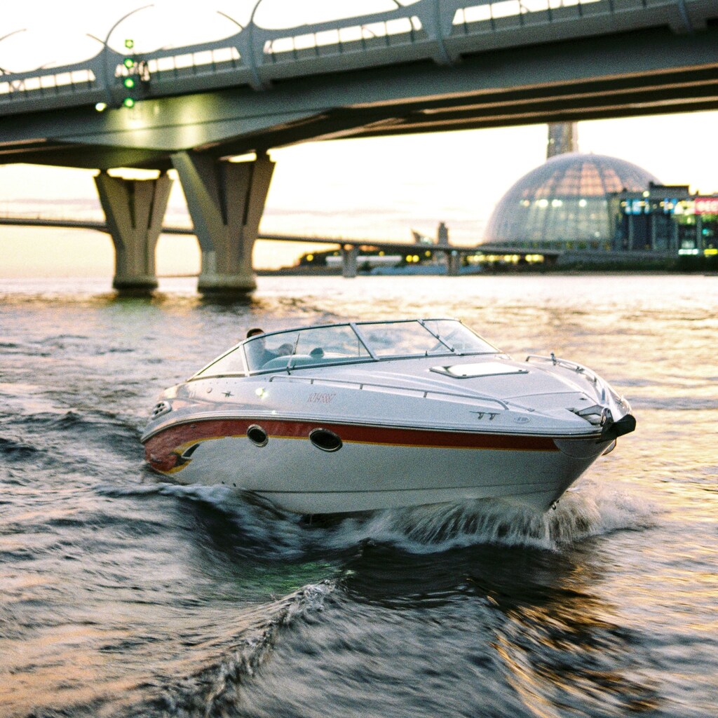 A photo of a speedboat cruising on a river beneath a modern bridge