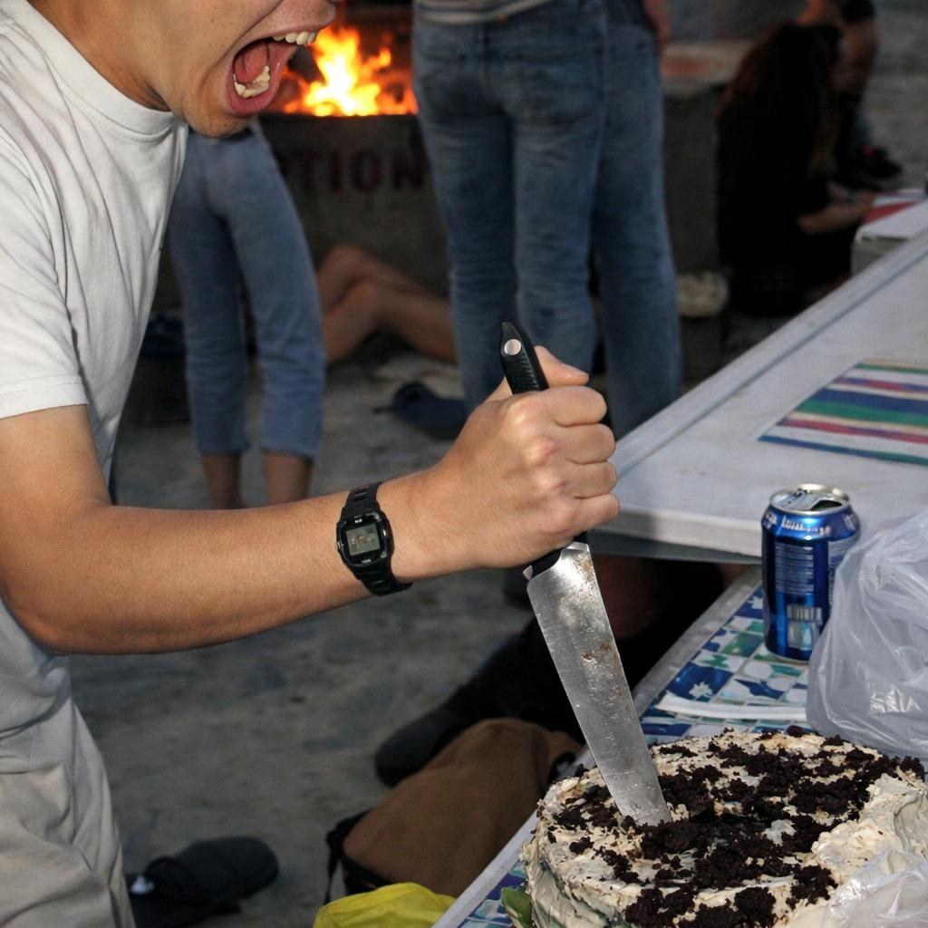 Photo of a man stabbing a cake