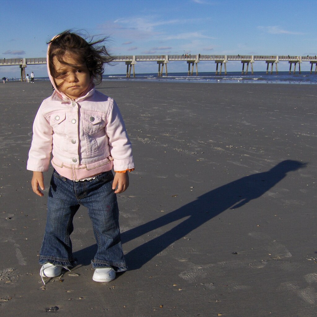 Photo of a little girl standing on a beach